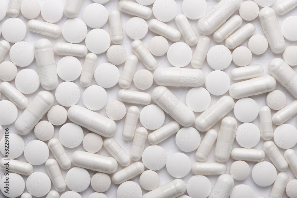White medication and supplements pills and capsules assortment background texture top view