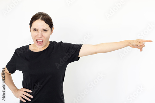 Woman screaming and pointing sideways. Furious Caucasian woman shouting with open mouth or arguing against white background. Negative emotion, anger, studio shot, expression concept
