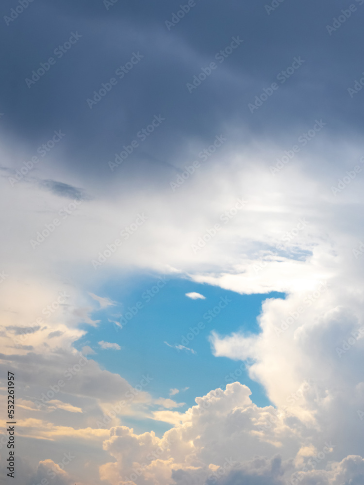 Fototapeta premium Dark and light clouds in the blue sky during sunset. A patch of blue sky peeks through the clouds