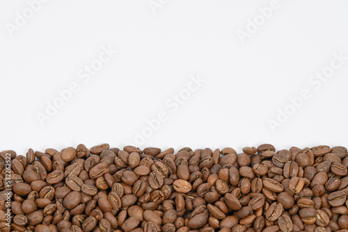 Coffee beans laid out in one wide row on a white background  place for inscription and advertising.