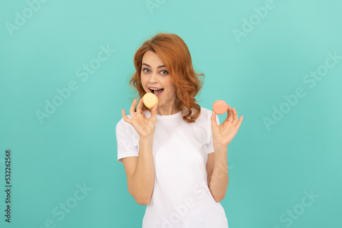 happy woman eat sweet macaron french cookie on blue background