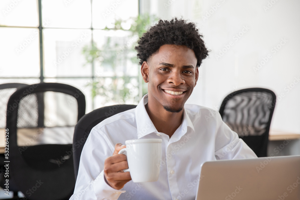 Portrait of happy male office worker drinking coffee. Smiling businessman in white shirt at desk looking at camera, holding cup. Business, coffee break, office work concept. Portrait of happy male office worker drinking coffee. Smiling businessman in white shirt at desk looking at camera, holding cup. Business, coffee break, office work concept.