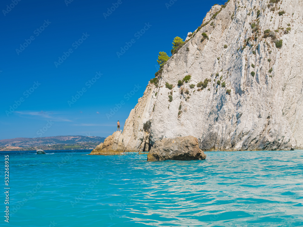 Fototapeta premium Man standing on a cliff of a rocky tropical beach