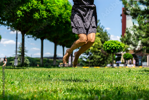 Naked female legs on tiptoe jumping barefoot against the backdrop of greenery in the park