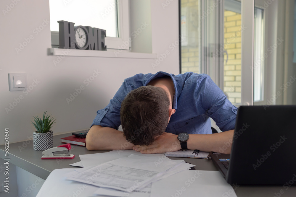 Frustrated with problems young business man working with papers and laptop computer at home. Frustrated with problems young business man working with papers and laptop computer at home.