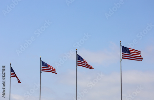 A row of American flags with blue sky copy space.