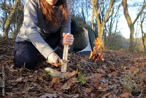 Close up of the hands of a caucasian woman sawing a branch with a hand saw in the forest. Female outdoors collecting wood to start up a fire. Concept of bushcraft and outdoor survival.