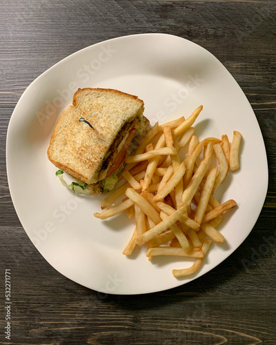 Half a grilled chicken sandwich with seasoned French fries.