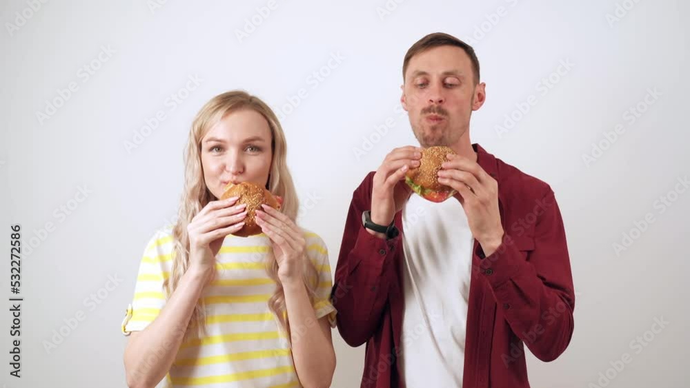 guy with a girl on a white background bite a hamburger. guy with a girl on a white background bite a hamburger.