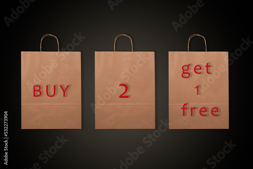 Paper bags with words Buy 2 Get 1 Free and black background