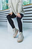 Close up of legs in stylish white shoes. Collection of women's shoes made of natural leather. Women's winter boots