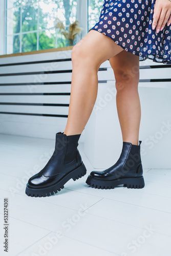 Close-up of black women's boots. Black boots made of genuine leather. Close-up photo of a woman's legs in warm boots