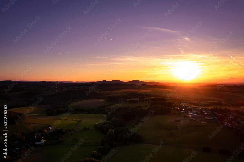 Aerial view of the countryside in the warm tones of sunset in Germany, dramatic sky
