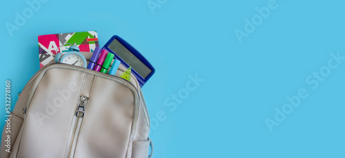 Backpack with school supplies on a colored background