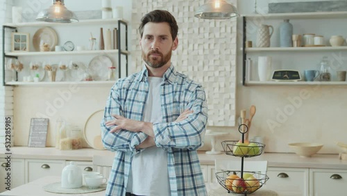 Portrait of confident bearded middle-aged man in kitchen spending free time alone at home. The man is nervous while waiting for the delivery