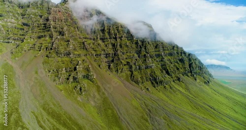 Shallow clouds hugging the ridge of a giantic mountain. photo