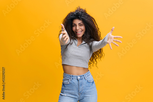 Valokuva Joyful young brunette curly latin woman in casual gray shirt isolated on yellow background