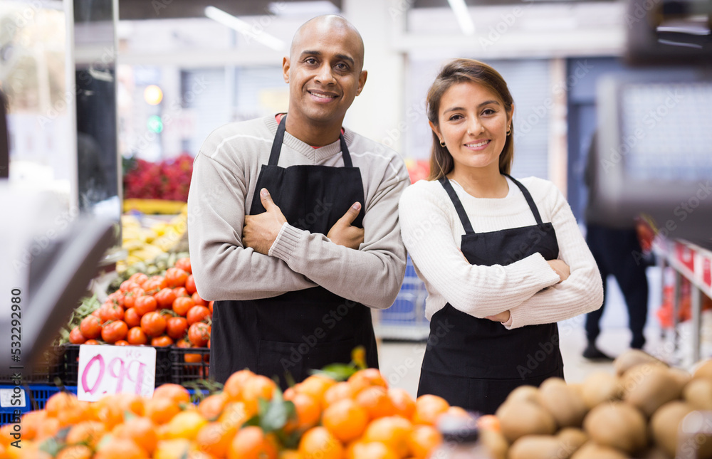 Horizontal portrait of hispanic man and woman wearing uniform standing together in supermarket