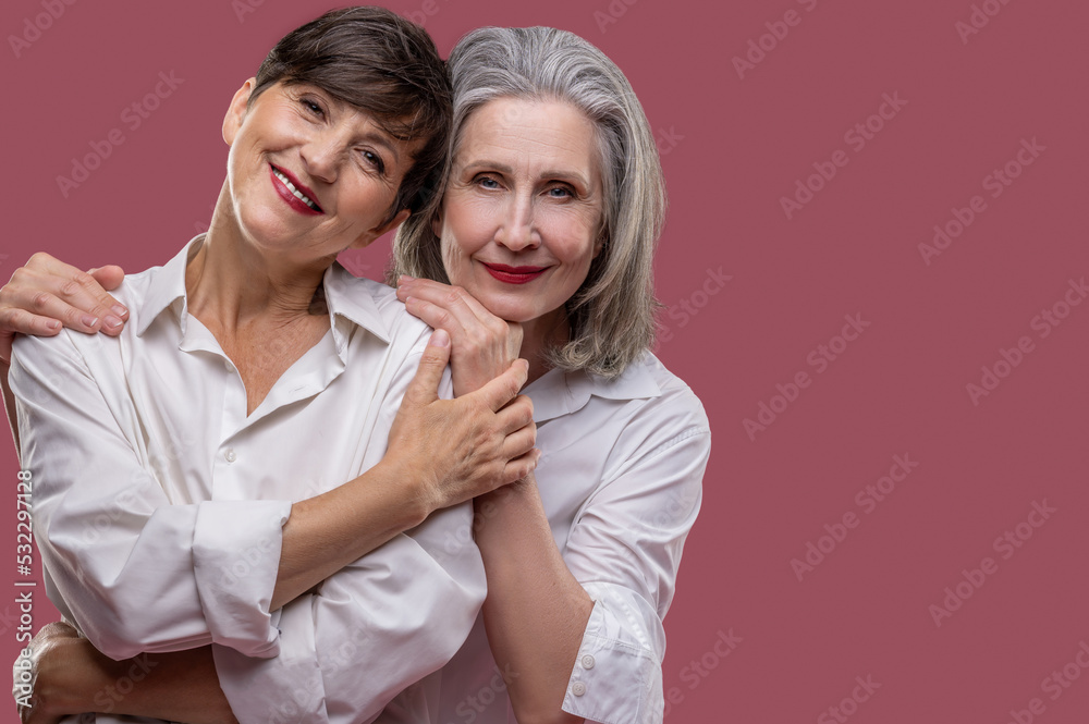 Two cute mature women standing together and hugging Two cute mature women standing together and hugging