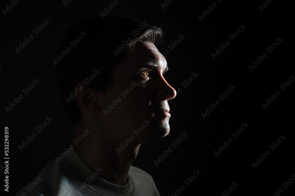 profile of thoughtful man looks to the right. portrait in side light, hard light, photo on black profile of thoughtful man looks to the right. portrait in side light, hard light, photo on black