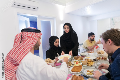 Eid Mubarak Muslim family having Iftar dinner drinking water to break feast. Eating traditional food during Ramadan feasting month at home. The Islamic Halal Eating and Drinking at modern western Isla photo