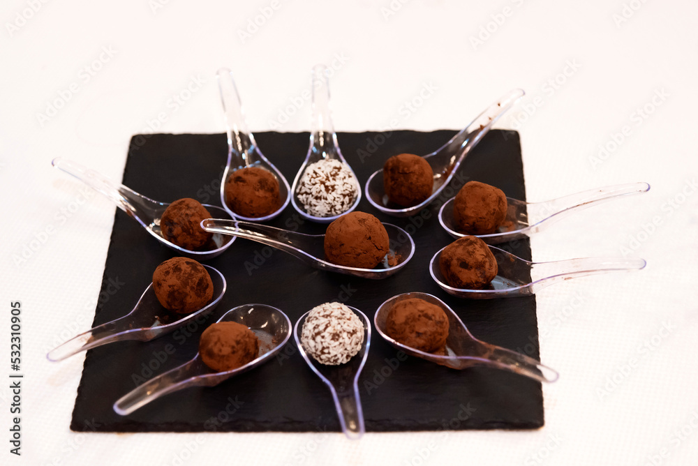 Chocolate truffles covered with cocoa powder in brown wooden bowl with dark chocolate pieces and cocoa powder in wooden spoon. Gray background. Top view table. Delicious candies, tasty dessert. Chocolate truffles covered with cocoa powder in brown wooden bowl with dark chocolate pieces and cocoa powder in wooden spoon. Gray background. Top view table. Delicious candies, tasty dessert.