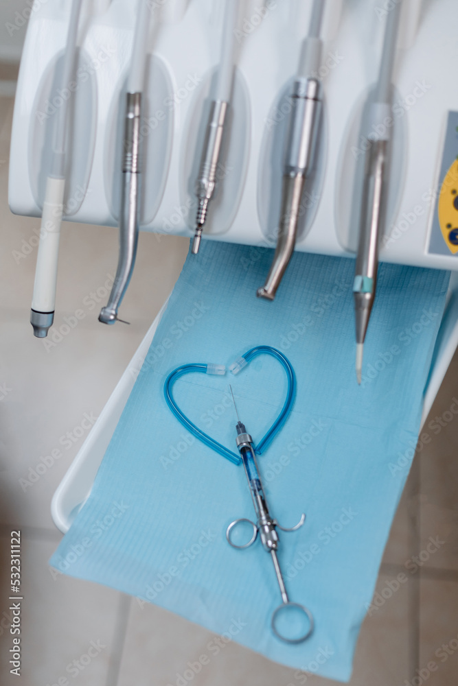 An injection for anesthesia of the tooth and a set of tools of the dental chair, close-up. Heart made of dentist's tools. An injection for anesthesia of the tooth and a set of tools of the dental chair, close-up. Heart made of dentist's tools.