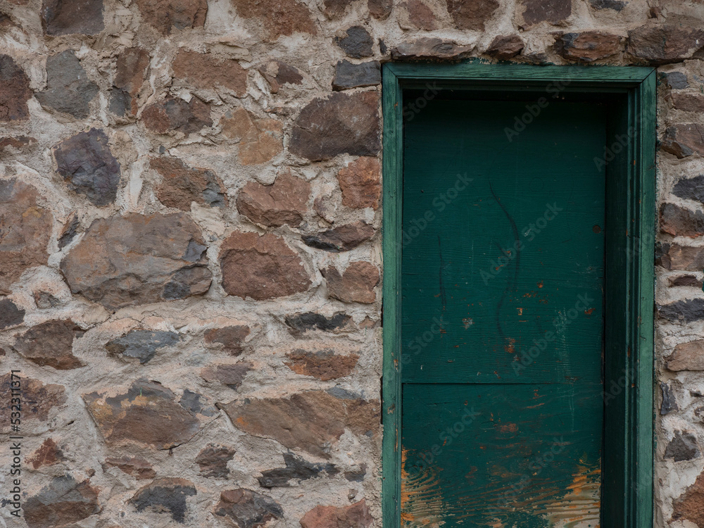 A rustic stone wall background with green door A rustic stone wall background with green door