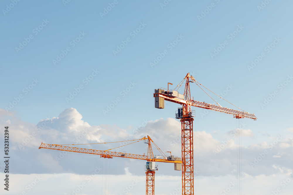building cranes at the construction site on blue sky background building cranes at the construction site on blue sky background