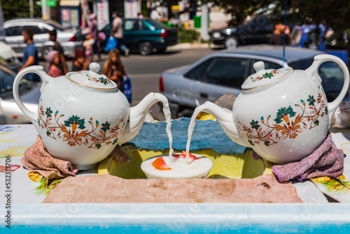Kulob, Khatlon Province, Tajikistan. Teapots pouring milk in a market. photo