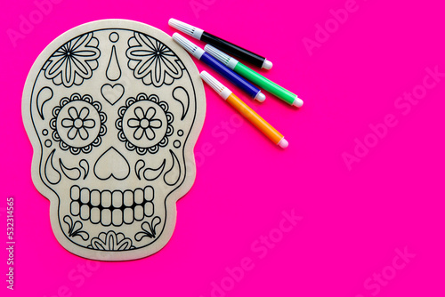 Wooden skull for drawing with colored pens on pink background. Day of the dead concept. Mexican traditional holiday photo