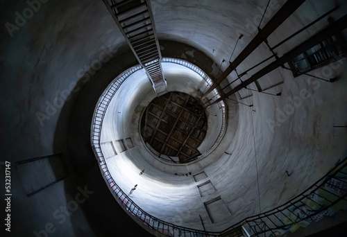 an old conical tower in the form of a spiral towering with a small stairway and piercing sunlight