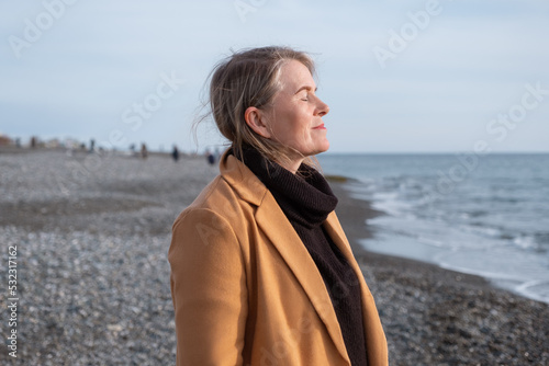 Mature woman breathing fresh air near sea