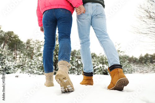 Couple walking in snowy forest on winter day, closeup