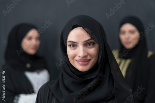 Group portrait of beautiful Muslim women in a fashionable dress with hijab isolated on black background