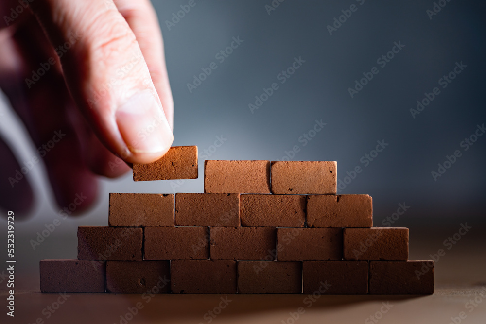 Hand placing wooden blocks stacked collapse prevention Hand placing wooden blocks stacked collapse prevention