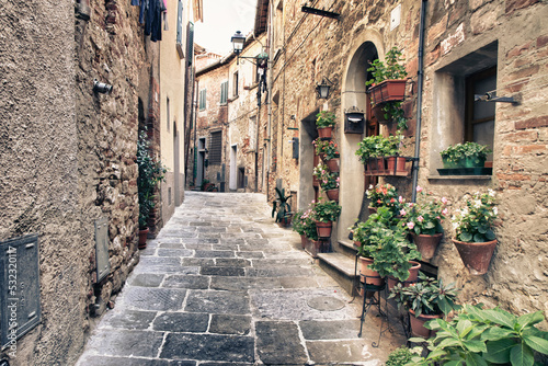 Italy, Tuscany, Crete Senesi, Asciano. Street scene with potted flowers near the entrance of a home in the hill town of Asciano. photo