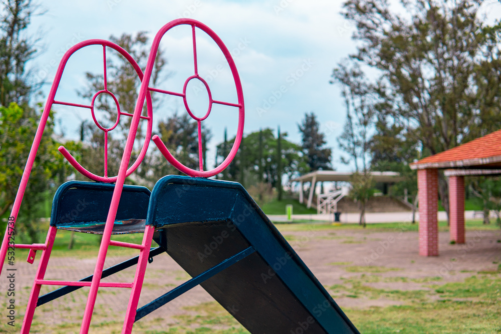 High quality photography. A blue slide in a park full of grass and nature. Close up to a slide. High quality photography. A blue slide in a park full of grass and nature. Close up to a slide.
