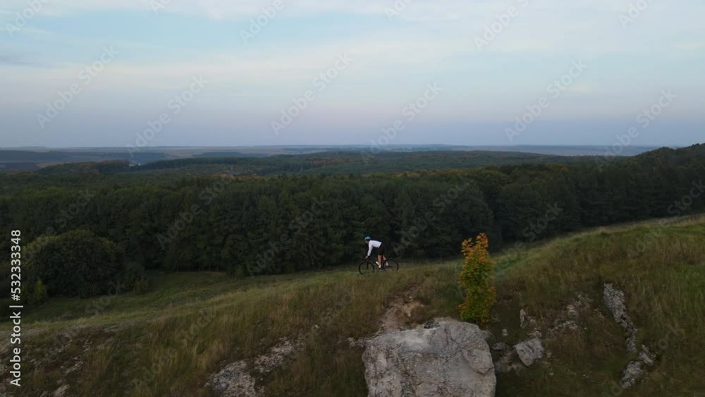 Aerial view on professional cyclist riding downhill with beautiful landscape on the background Aerial view on professional cyclist riding downhill with beautiful landscape on the background