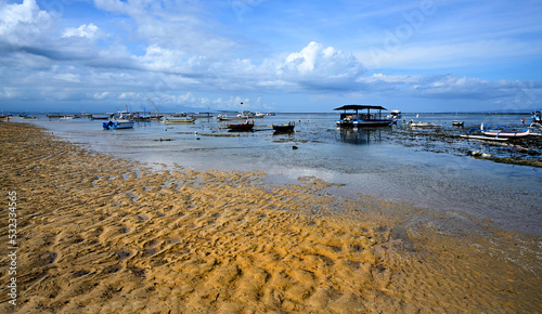 Sun at low tide silhouettes several fishing boats, Bali Indonesia photo