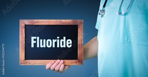 Fluoride. Doctor shows sign/board with wooden frame. Background blue