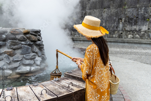 Travel woman put a basket into hot spring for cooking in Jioujhihze of Taipingshan in Taiwan photo