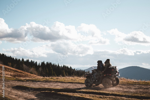 People on ATV are driving offroad in mountains during autumn sunny day