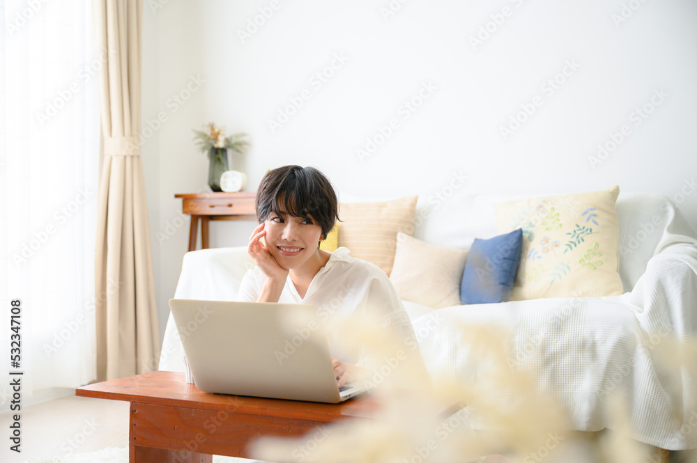 Woman in room with computer in soft backlight, looking at camera, with front blur. Woman in room with computer in soft backlight, looking at camera, with front blur.