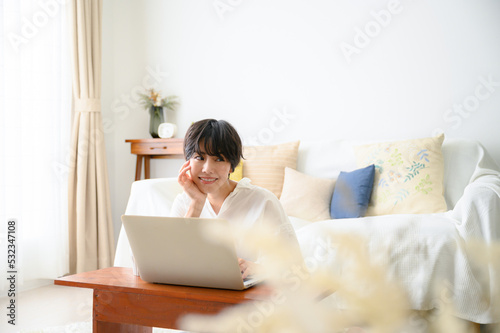 Woman in room with computer in soft backlight, looking at camera, with front blur.