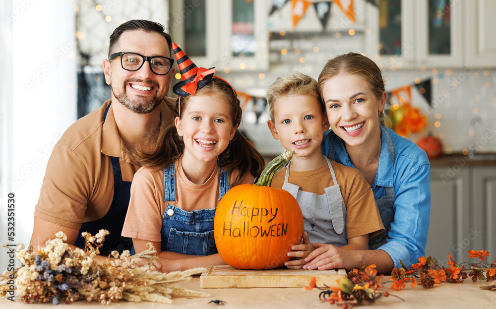 Fototapeta premium Happy family mother, father and children smiling at camera with pumpkin during celebration, preparing home Halloween decorations