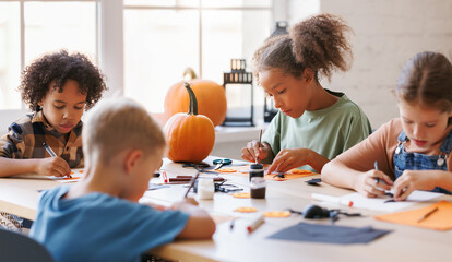 Happy multinational group of children making Halloween home decorations together