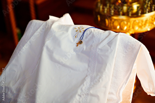 Billede på lærred a white baptismal shirt and a cross on a table in the church during baptism