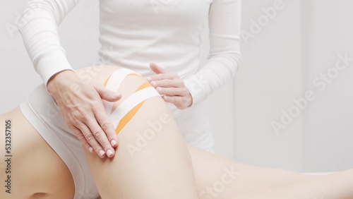 Therapist is applying tape to female body. Physiotherapy, kinesiology and recovery treatment.