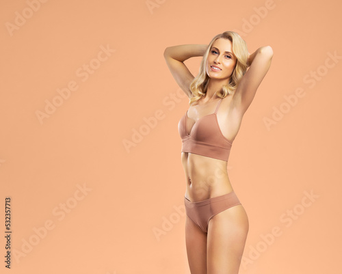 Young, fit and beautiful blond woman in white swimsuit over grey background. Healthcare, diet, sport and fitness concept.